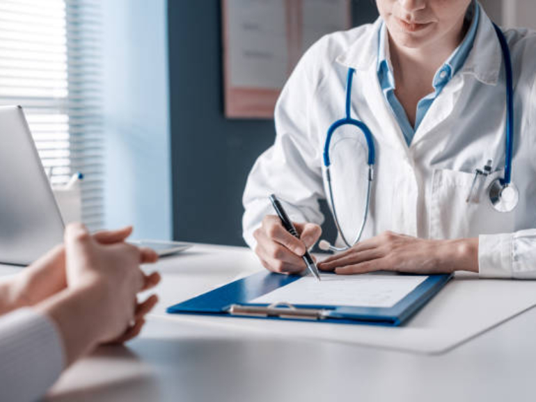 Doctor sitting at desk and writing a prescription for her patient